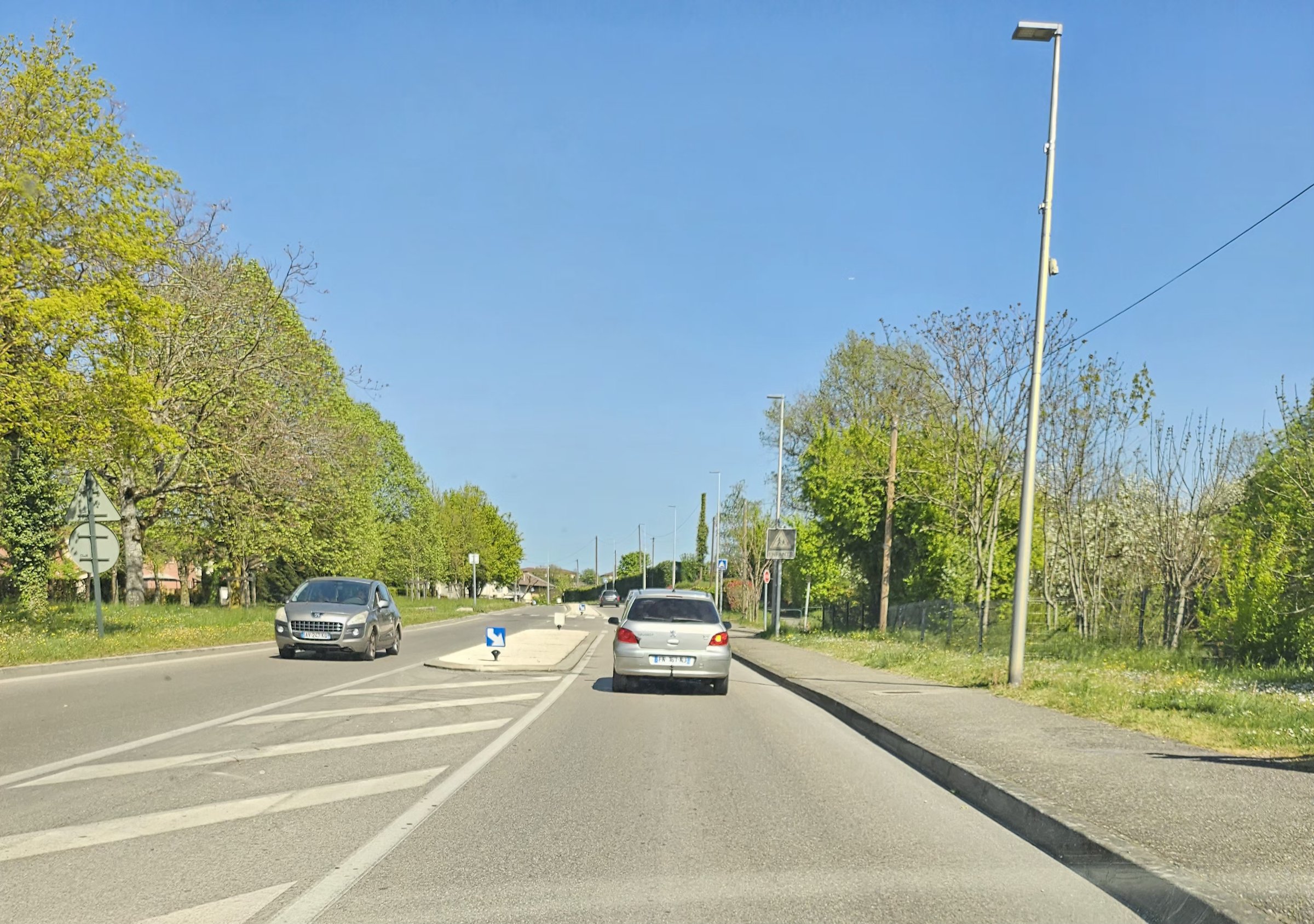 Route française péri-urbaine avec panneaux de signalisation et passages piétons — environnement typique de l'apprentissage de la sécurité routière au collège (ASSR1)