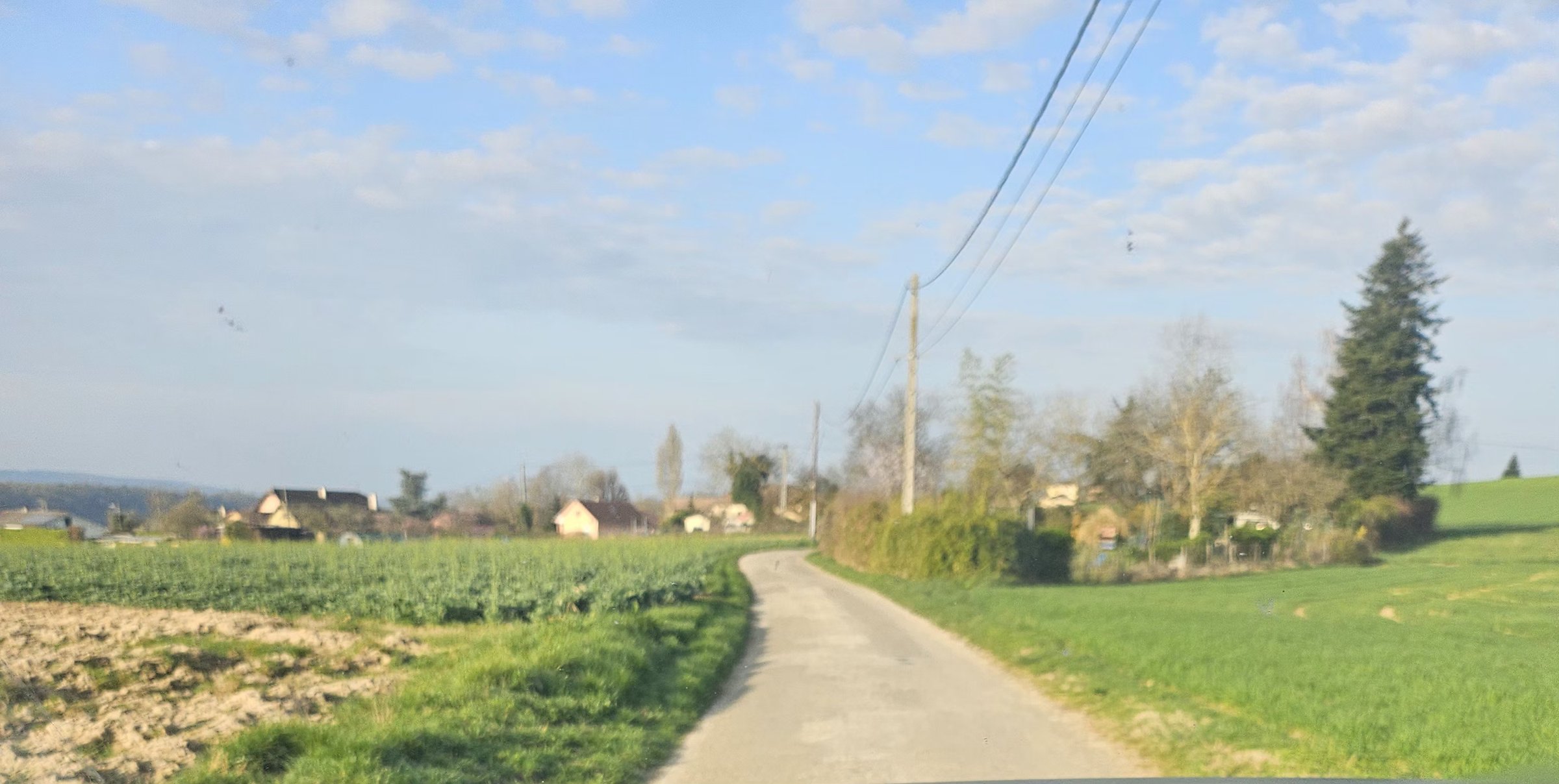 Route rurale sinueuse française traversant des champs verts — environnement typique de l'apprentissage de la trajectoire de sécurité en virage